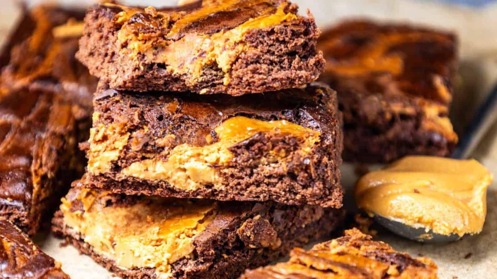 A stack of rich peanut butter brownies with a spoonful of creamy peanut butter on the side.