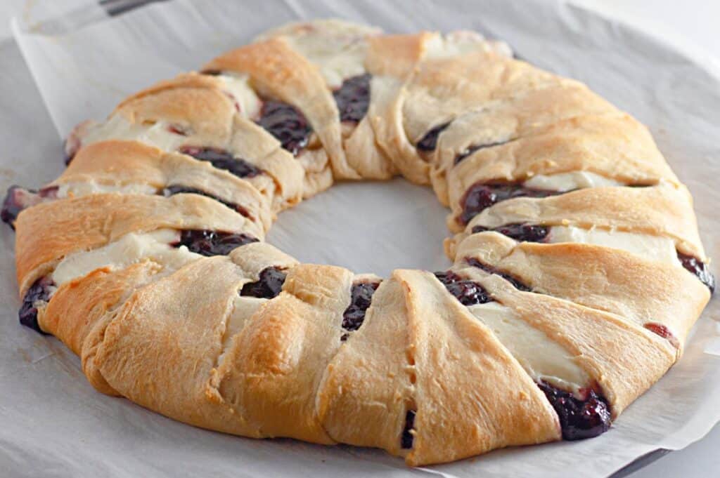 freshly baked raspberry crescent ring with cream cheese filling, resting on parchment paper.