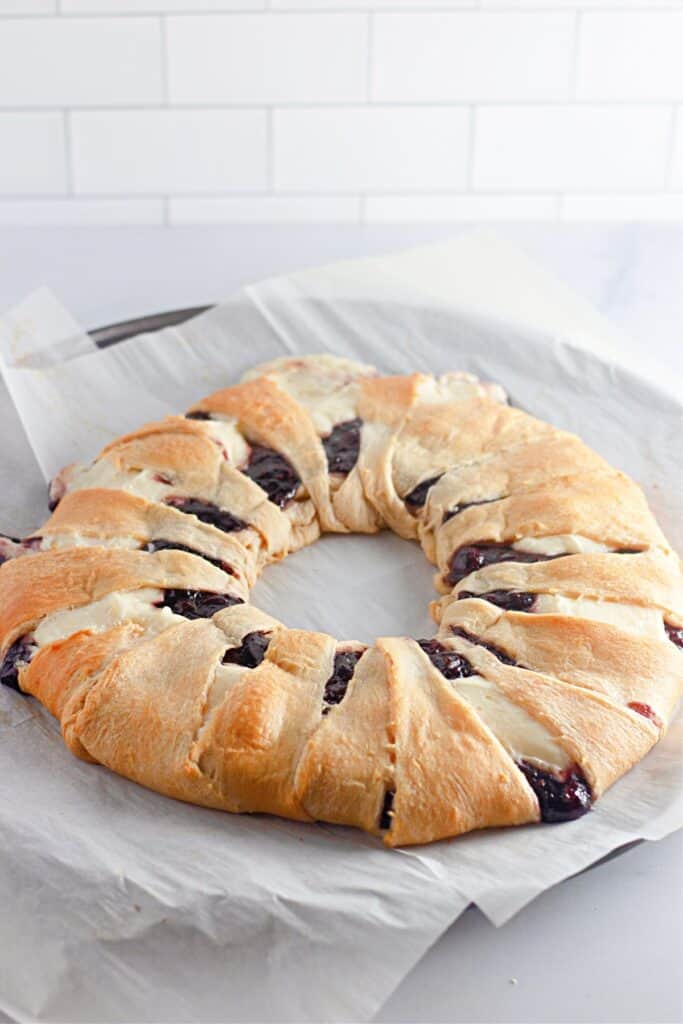 Freshly baked raspberry crescent ring with cream cheese filling, placed on parchment paper.