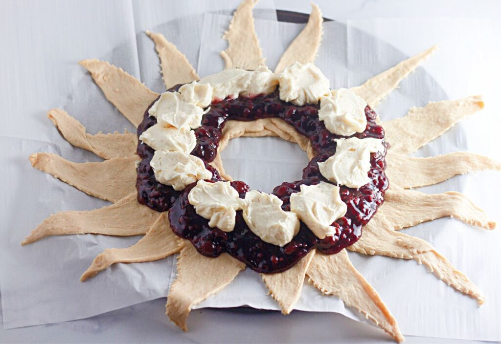 Dollops of sweetened cream cheese layered over raspberry pie filling in the center of the crescent dough ring.
