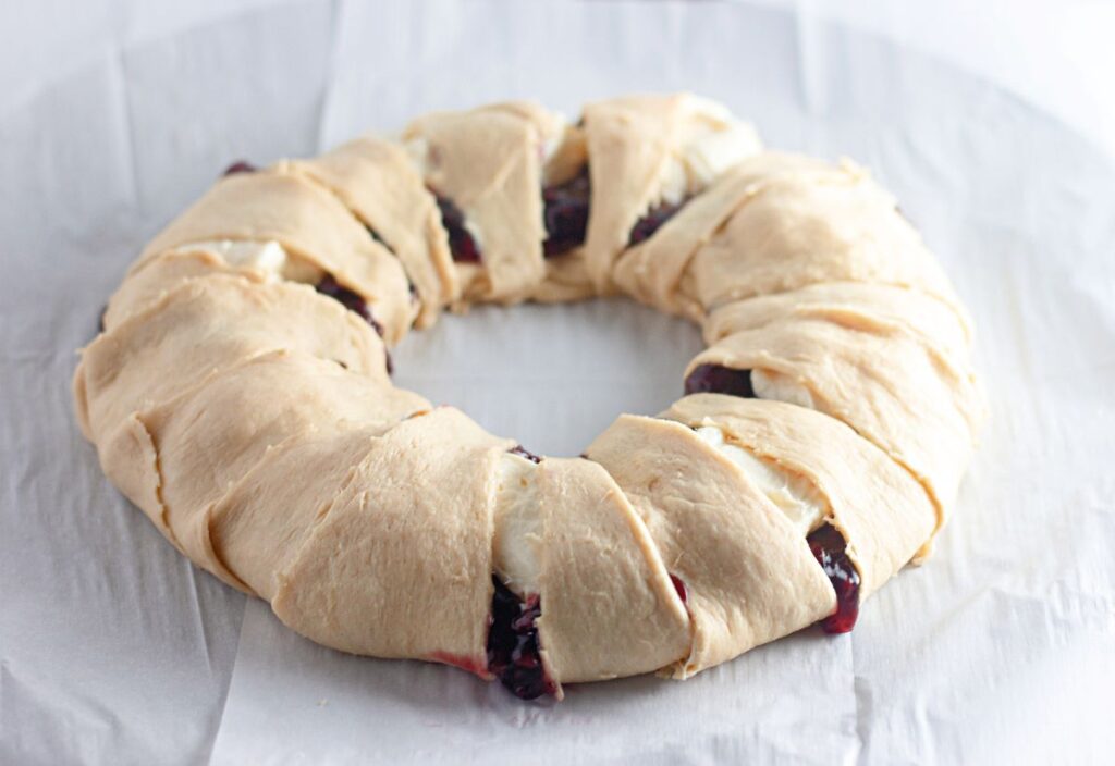 Crescent dough ends folded over the raspberry and cream cheese filling to form a sealed ring before baking.