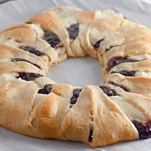 freshly baked raspberry crescent ring with cream cheese filling, resting on parchment paper.