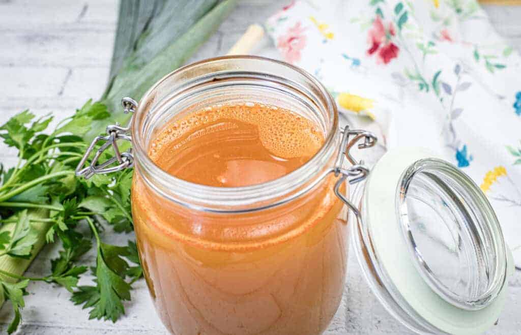 A glass jar filled with shrimp stock.