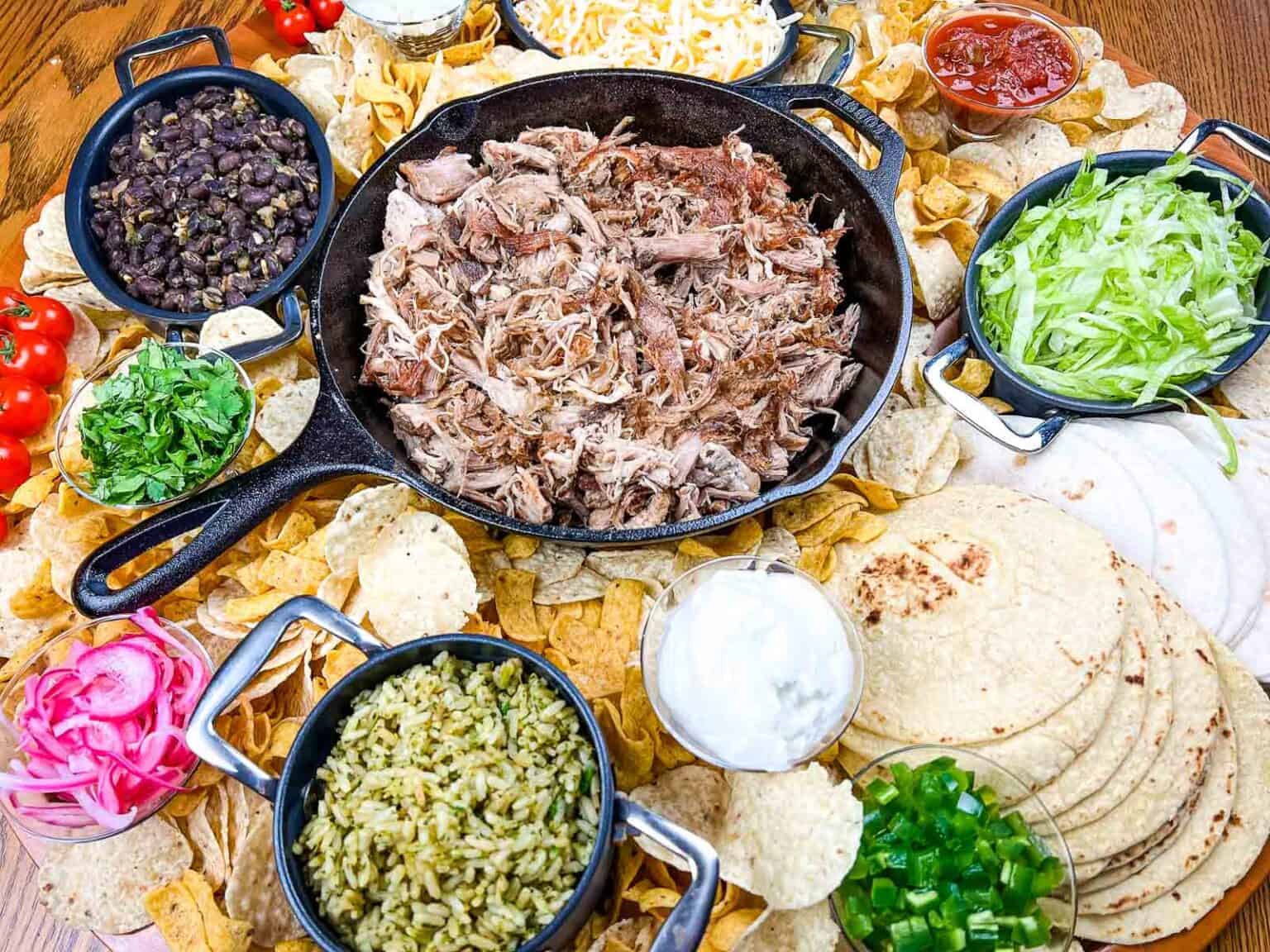 A platter of pork carnitas board on a wooden table.