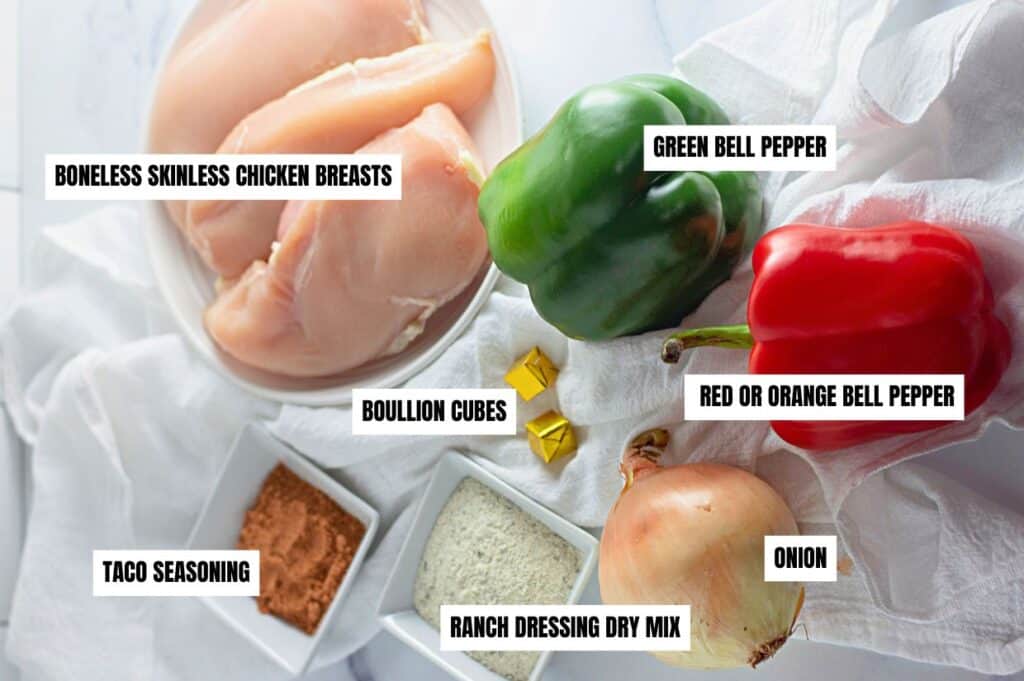 Ingredients for slow cooker chicken tacos, including boneless skinless chicken breasts, green and red bell peppers, onion, bouillon cubes, taco seasoning, and ranch dressing dry mix.