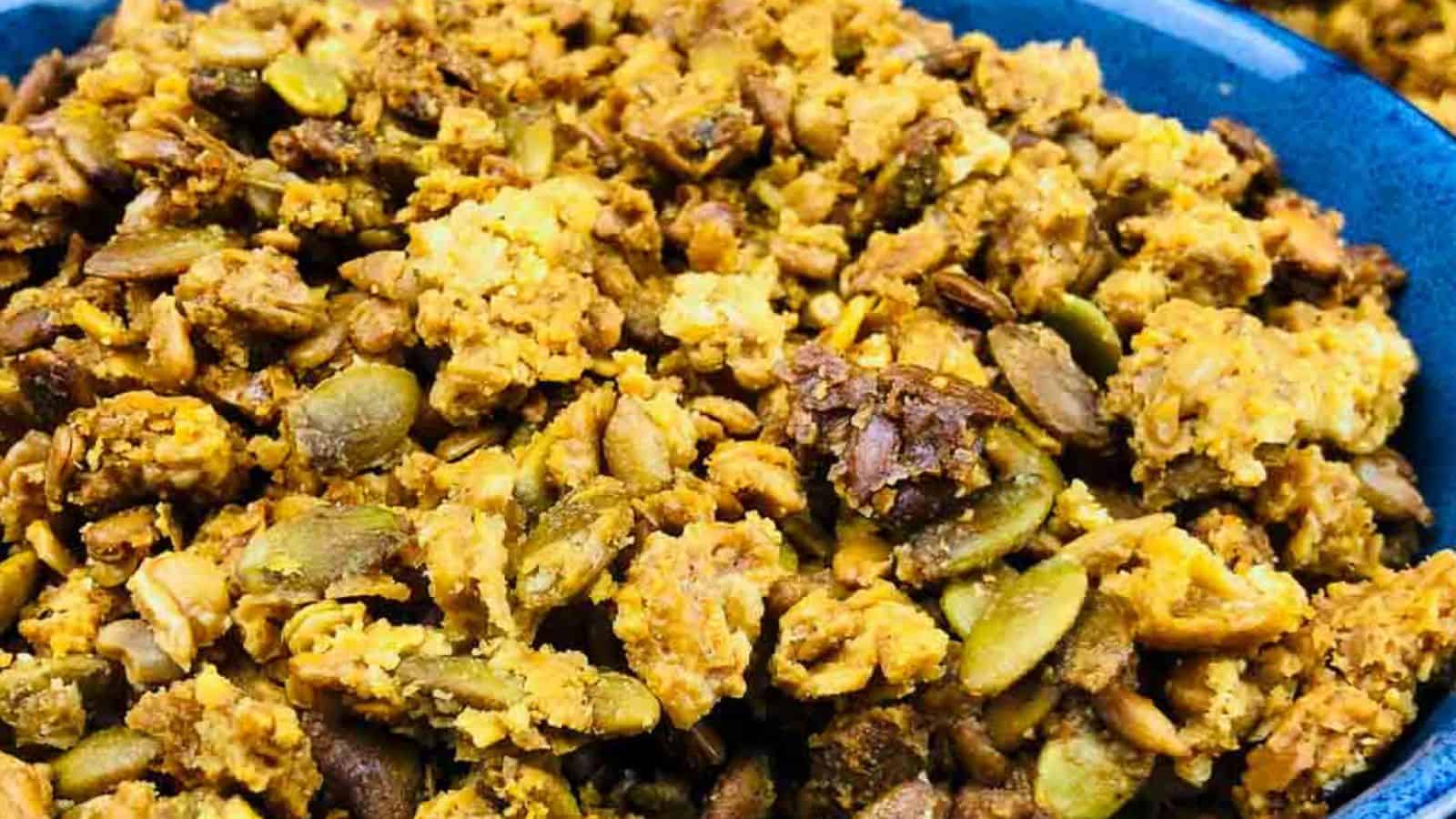 Close-up image of a bowl filled with granola, featuring a mix of nuts, seeds, and clusters of oats.