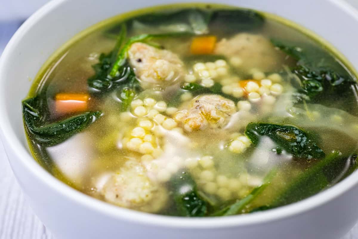 A white bowl of Italian Wedding Soup.