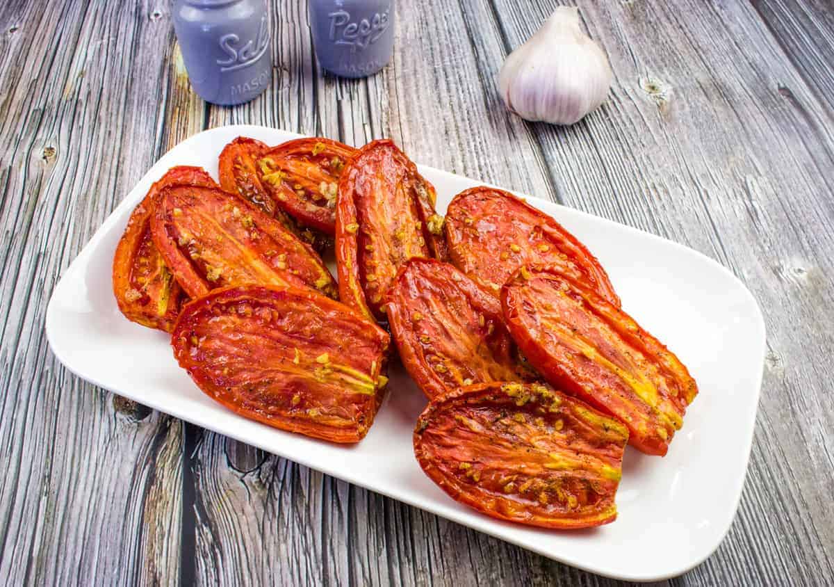 Smoked tomatoes served on a white rectangular plate.