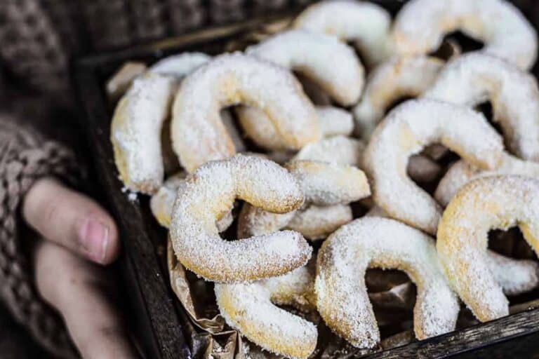 A tray of crescent-shaped cookies dusted with powdered sugar.