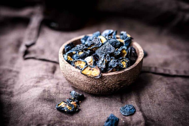 A bowl filled with dark blue dried blueberries.