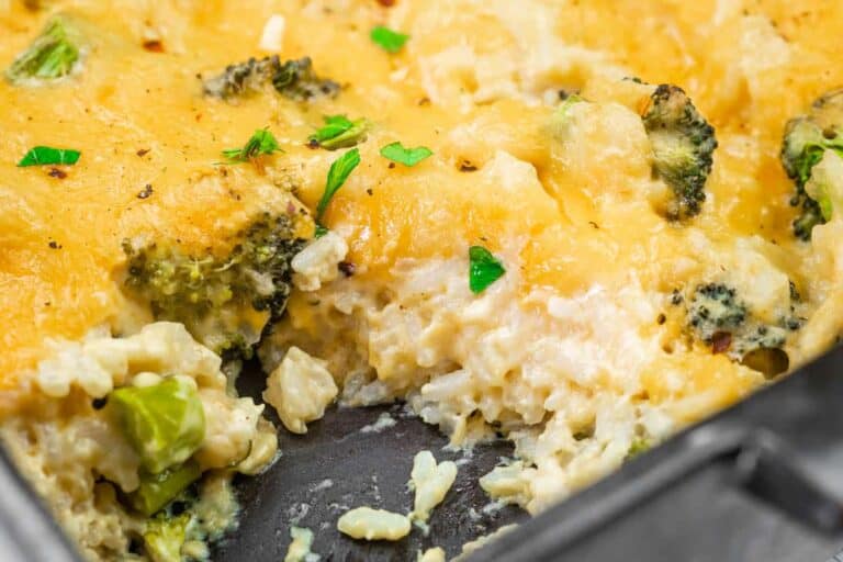 Close-up of a Broccoli Rice Casserole with a portion missing, garnished with parsley in a baking dish.