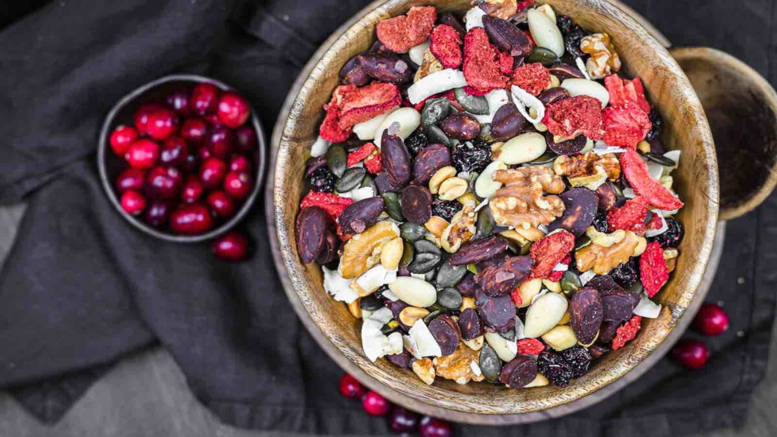 A wooden bowl filled with a mix of dried fruits, seeds, and nuts.