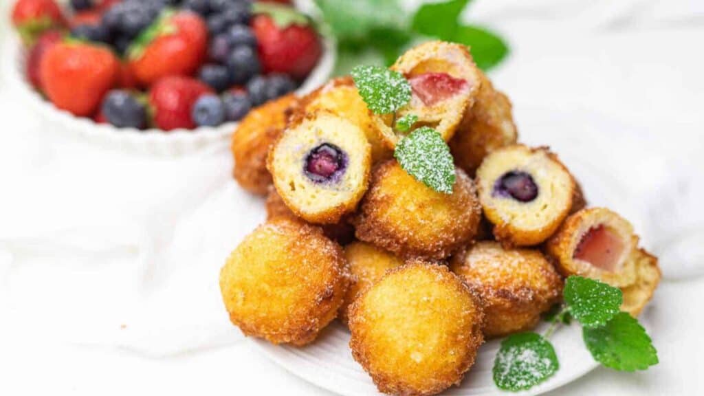 Mini Cheesecake Bites garnished with mint and a plate of berries on the side.