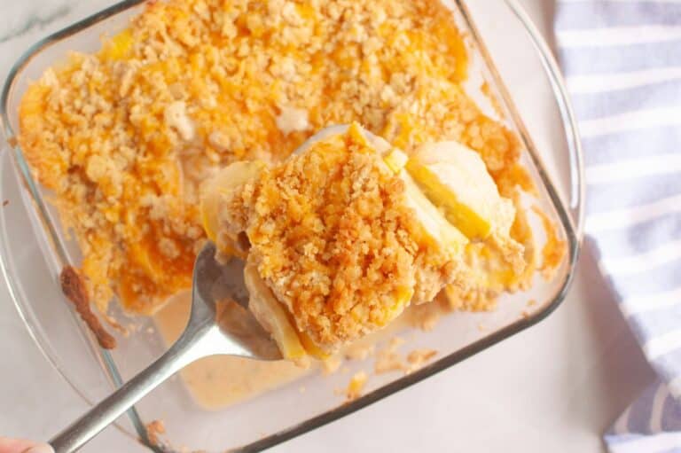 A close-up of a serving of Southern Squash Casserole being lifted from a glass baking dish.