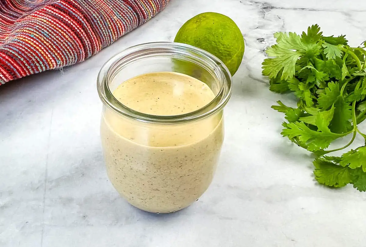 A jar with a lime and cilantro next to it.