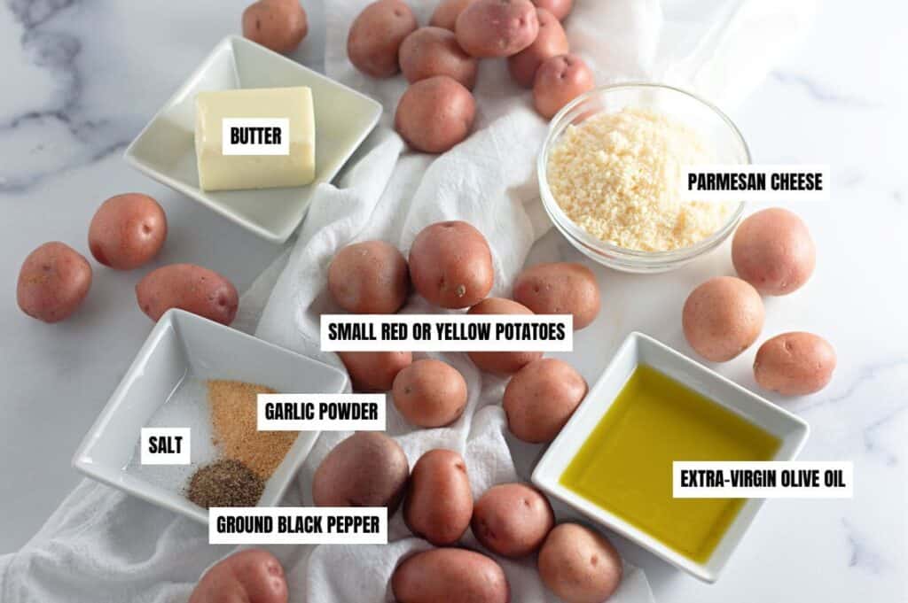 A flat lay of ingredients for crispy garlic Parmesan smashed potatoes, including small red potatoes, butter, Parmesan cheese, olive oil, and seasonings like garlic powder, salt, and black pepper.