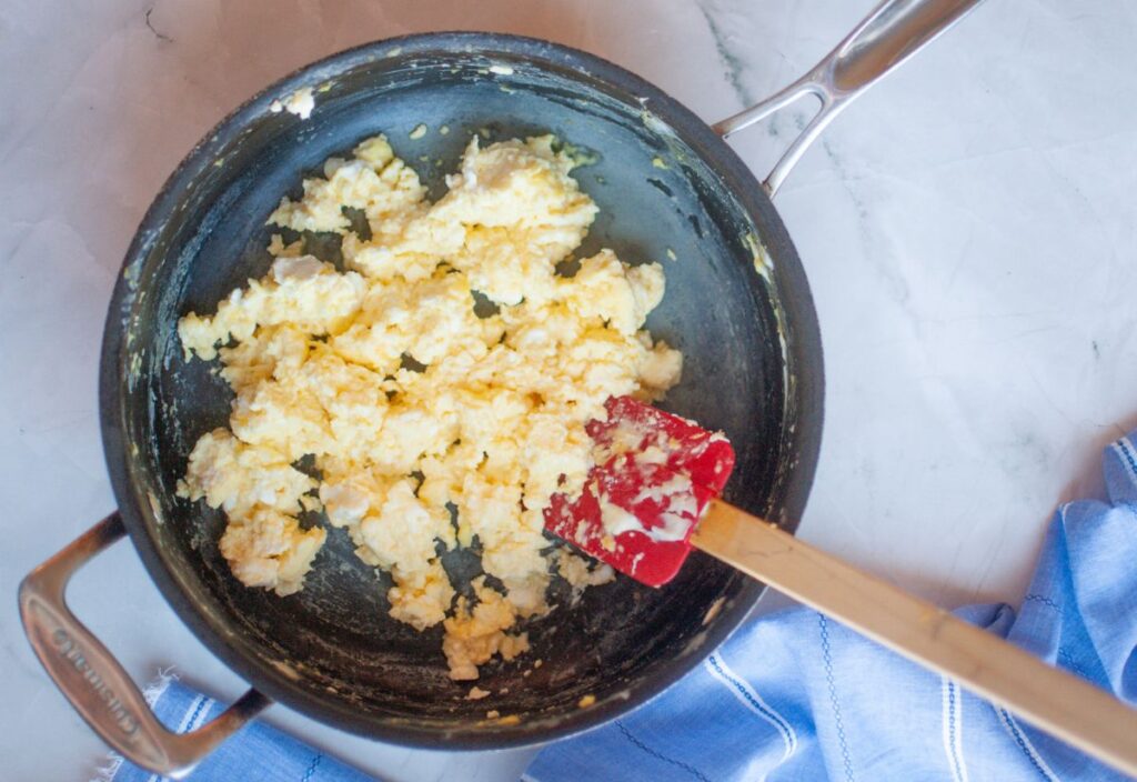 Creamy scrambled eggs in non-stick pan with spatula.