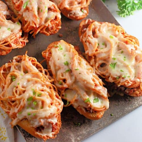 Toasted bread slices topped with spaghetti, marinara sauce, and melted mozzarella cheese, garnished with fresh parsley. A creative and cheesy twist on classic spaghetti, served open-faced and oven-baked.