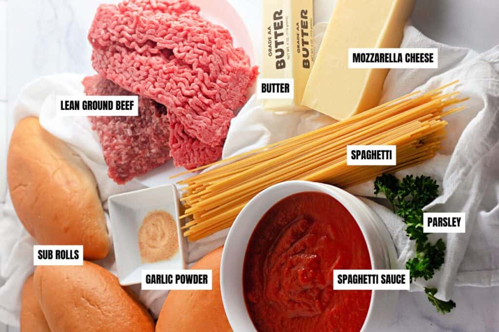 Ingredients for spaghetti bread arranged on a surface, including lean ground beef, sub rolls, garlic powder, spaghetti, spaghetti sauce, parsley, butter, and mozzarella cheese.