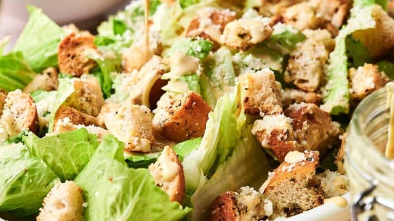 A Caesar salad with romaine lettuce, croutons, grated cheese, and dressing.