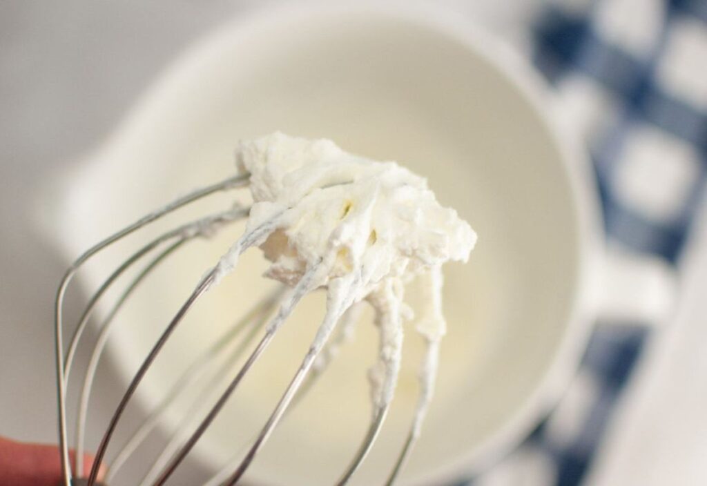 Whisking heavy cream to stiff peaks for the trifle.