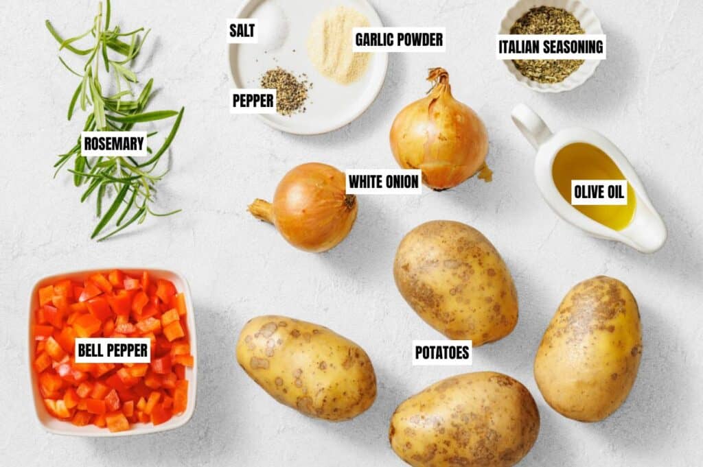 Ingredients for a savory dish are arranged on a light surface: rosemary, diced bell peppers, potatoes, white onions, olive oil, salt, pepper, garlic powder, and Italian seasoning.