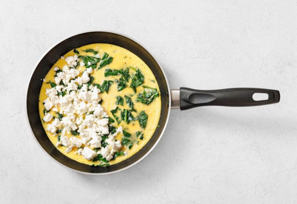 A cooked omelet with spinach and goat cheese in a non-stick pan.
