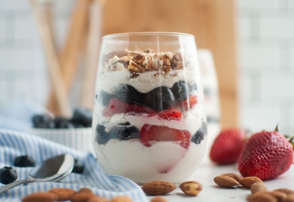 A delicious berry trifle layered with fresh strawberries, blueberries, and creamy layers, topped with crushed almonds for added texture.