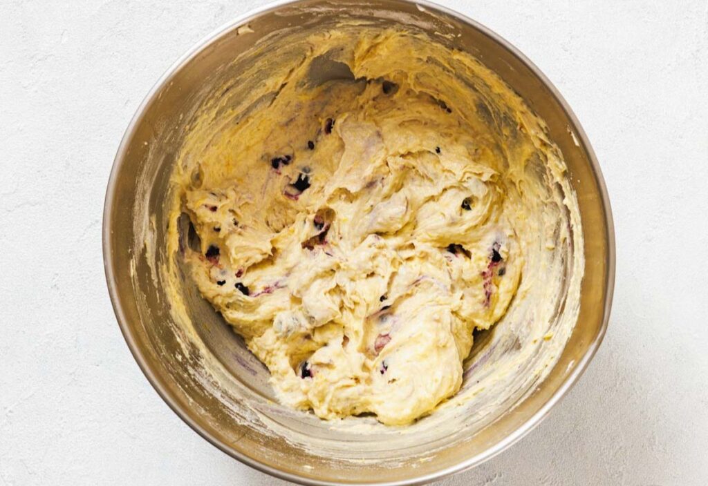 A bowl of creamy batter with blueberries mixed in.