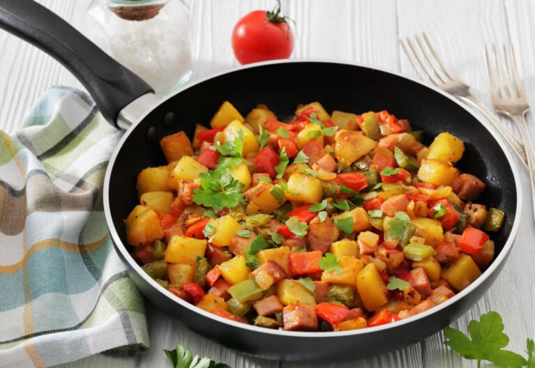 A skillet filled with colorful sautéed vegetables, including potatoes, red and green peppers, garnished with parsley. A vibrant, fresh meal setting.