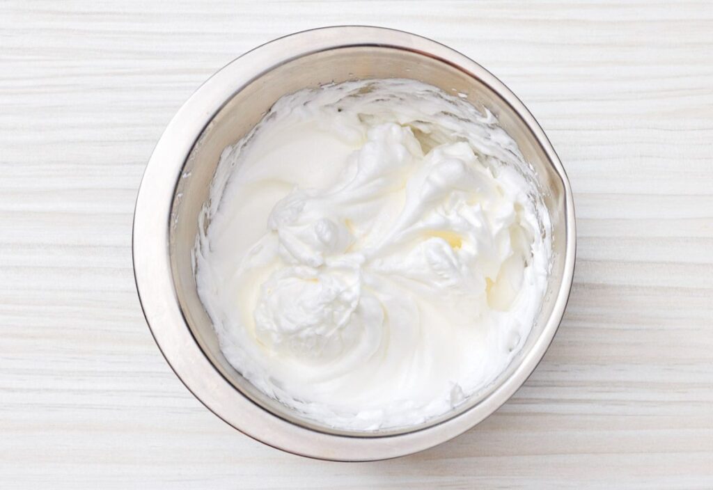 A bowl with whipped egg whites, showing soft peaks and a smooth texture.