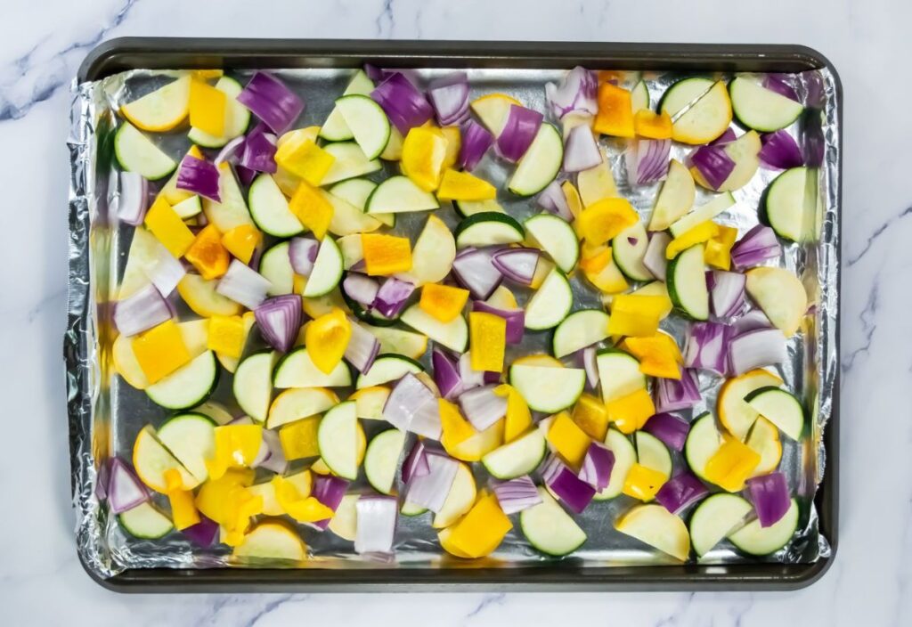 Added onions and bell peppers on the baking sheet with zucchini and squash.