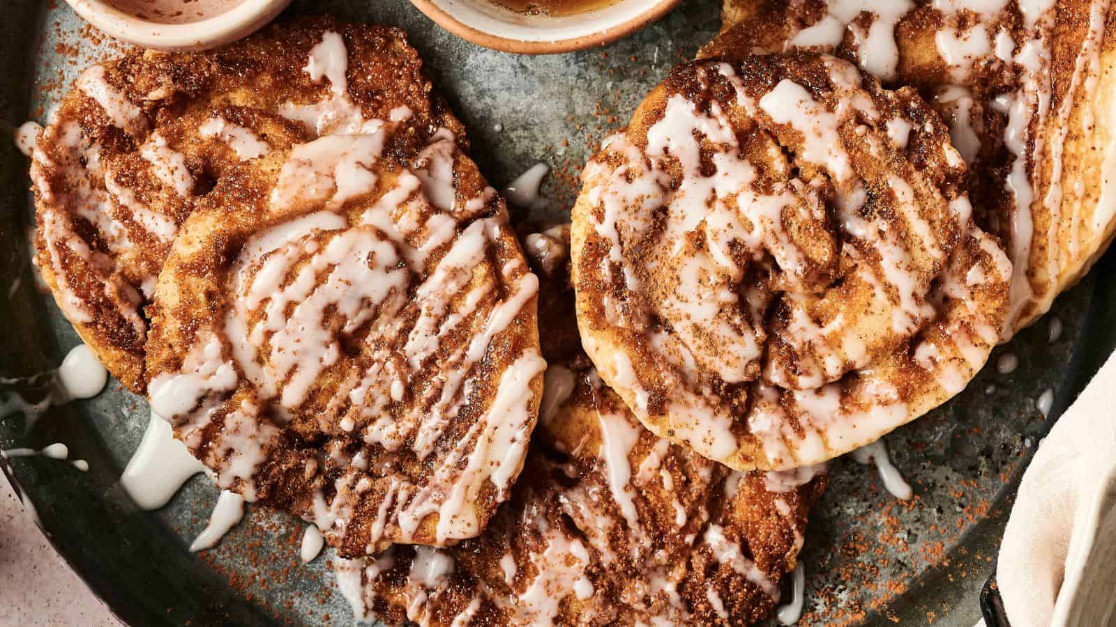 Close-up of cinnamon rolls drizzled with white icing on a plate.
