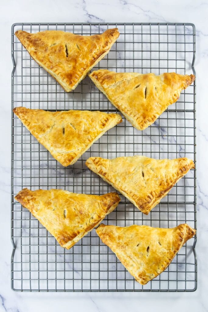 A batch of freshly baked triangular pastries resting on a cooling rack.