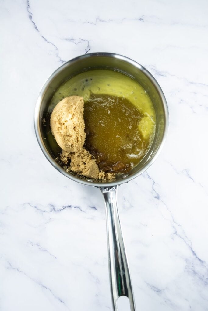 Brown sugar and honey added to melted butter in a saucepan, preparing the base for the brittle.