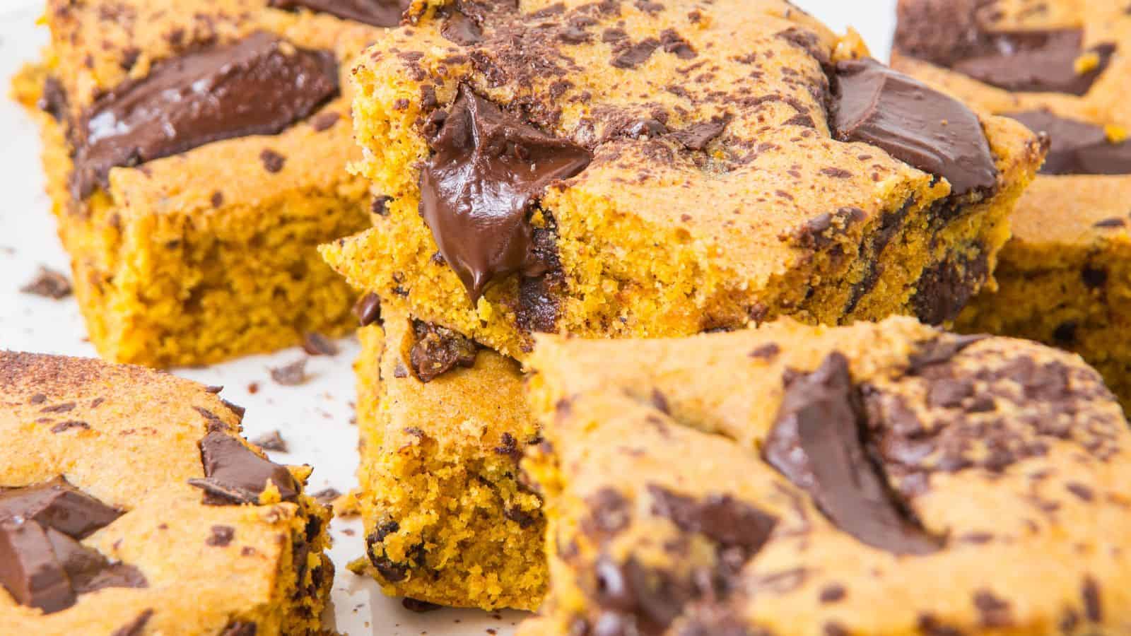 Close-up of pumpkin chocolate bars stacked on a plate, showcasing their golden orange color and melty chocolate chunks.