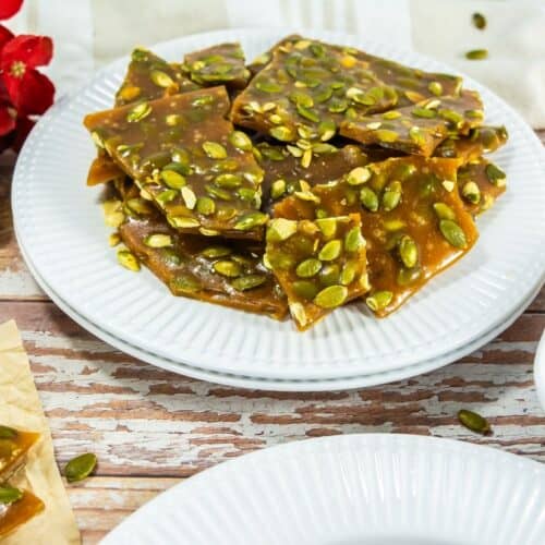 A plate of pumpkin seed brittle with a crunchy texture and garnished with pumpkin seeds.