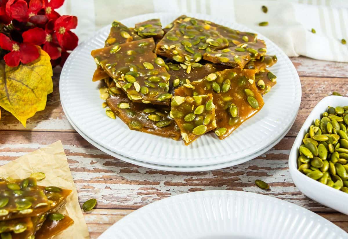 A plate of pumpkin seed brittle with a crunchy texture and garnished with pumpkin seeds.