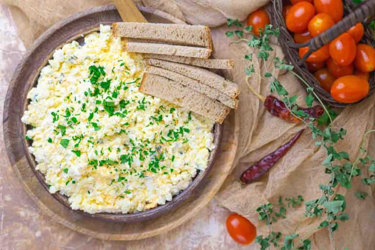 Scrambled eggs served with sliced whole wheat bread and cherry tomatoes on the side.