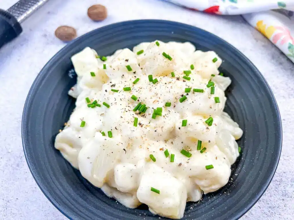 German Kohlrabi in Cream Sauce on a black plate.