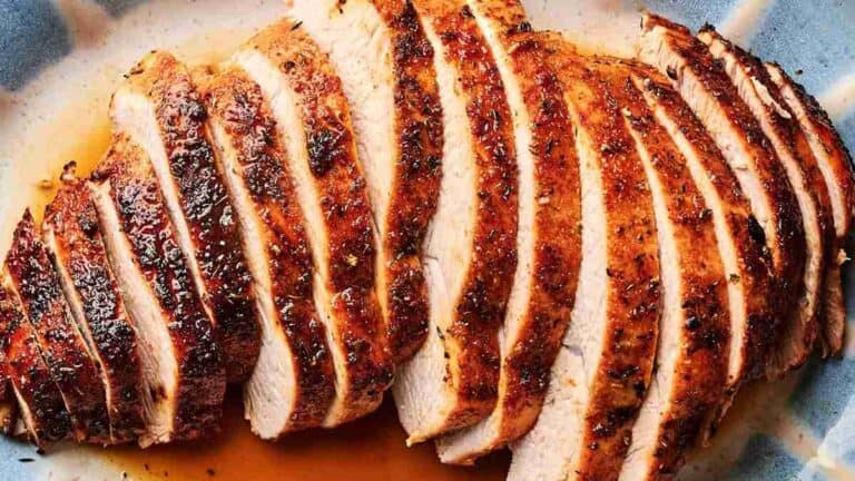 A close-up of roasted turkey breast, sliced and arranged on a plate.