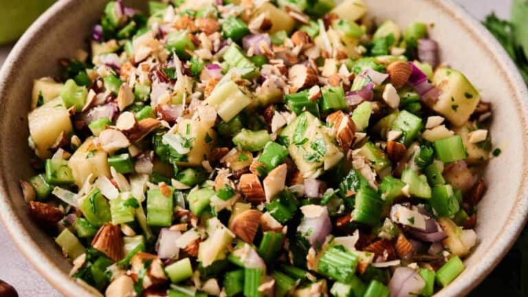 A fresh celery salad with chopped almonds, green apple pieces, and a vinaigrette dressing.