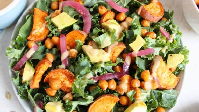A fall-inspired harvest salad with roasted vegetables, greens, nuts, and fruit slices.