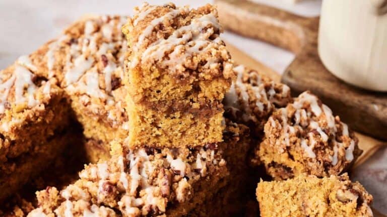 A pumpkin coffee cake topped with a cinnamon streusel and glaze, showcasing a moist, spongy texture.