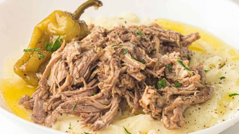 A close-up of pulled pork served on a plate with green bell peppers, garnished with chopped cilantro.