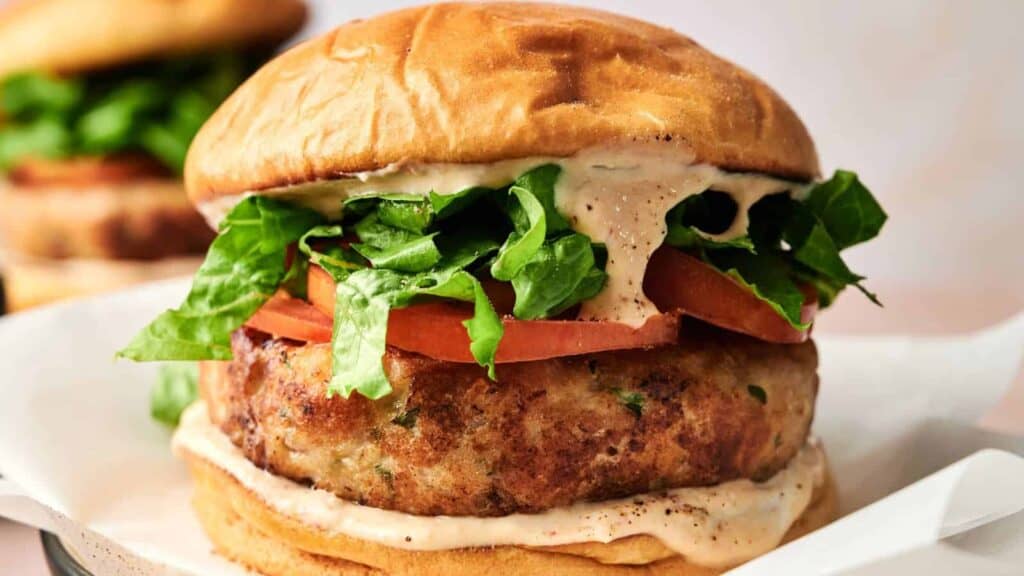 Homemade turkey burger with lettuce, tomato, and creamy sauce on a soft bun.