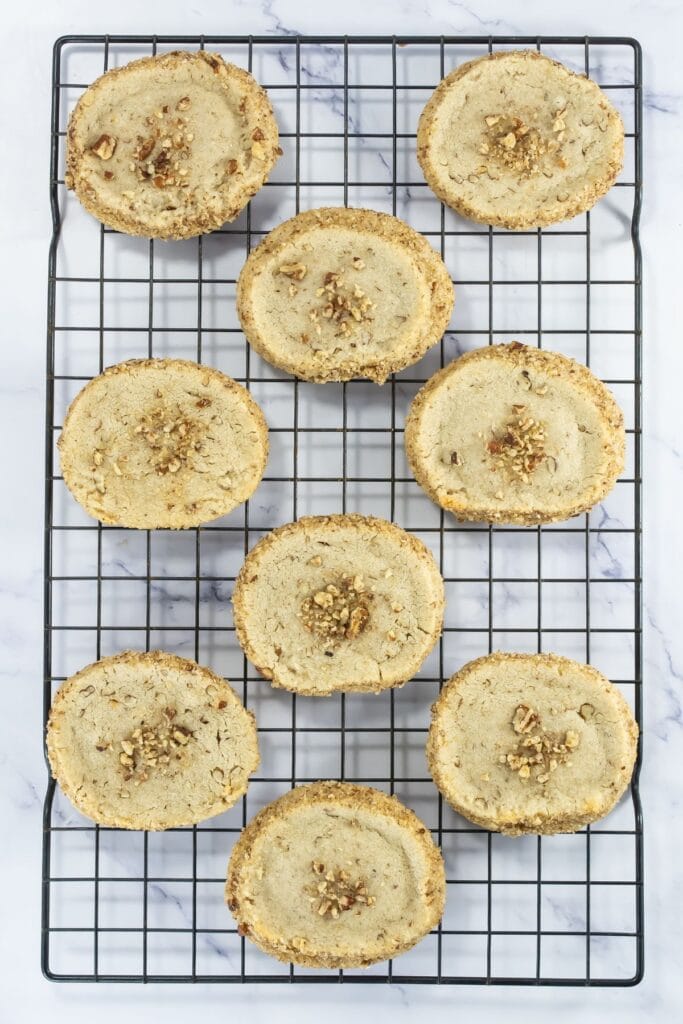 Freshly baked pecan shortbread cookies cooling on a black wire rack.