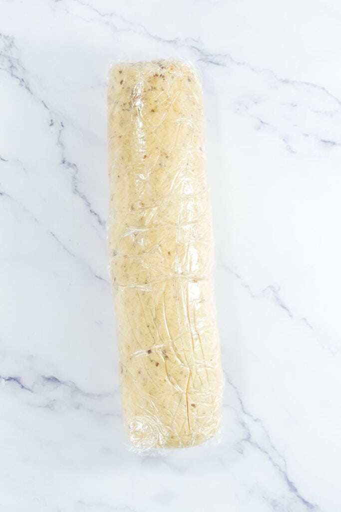 baked pecan shortbread dough shaped into a log and wrapped tightly in plastic wrap.