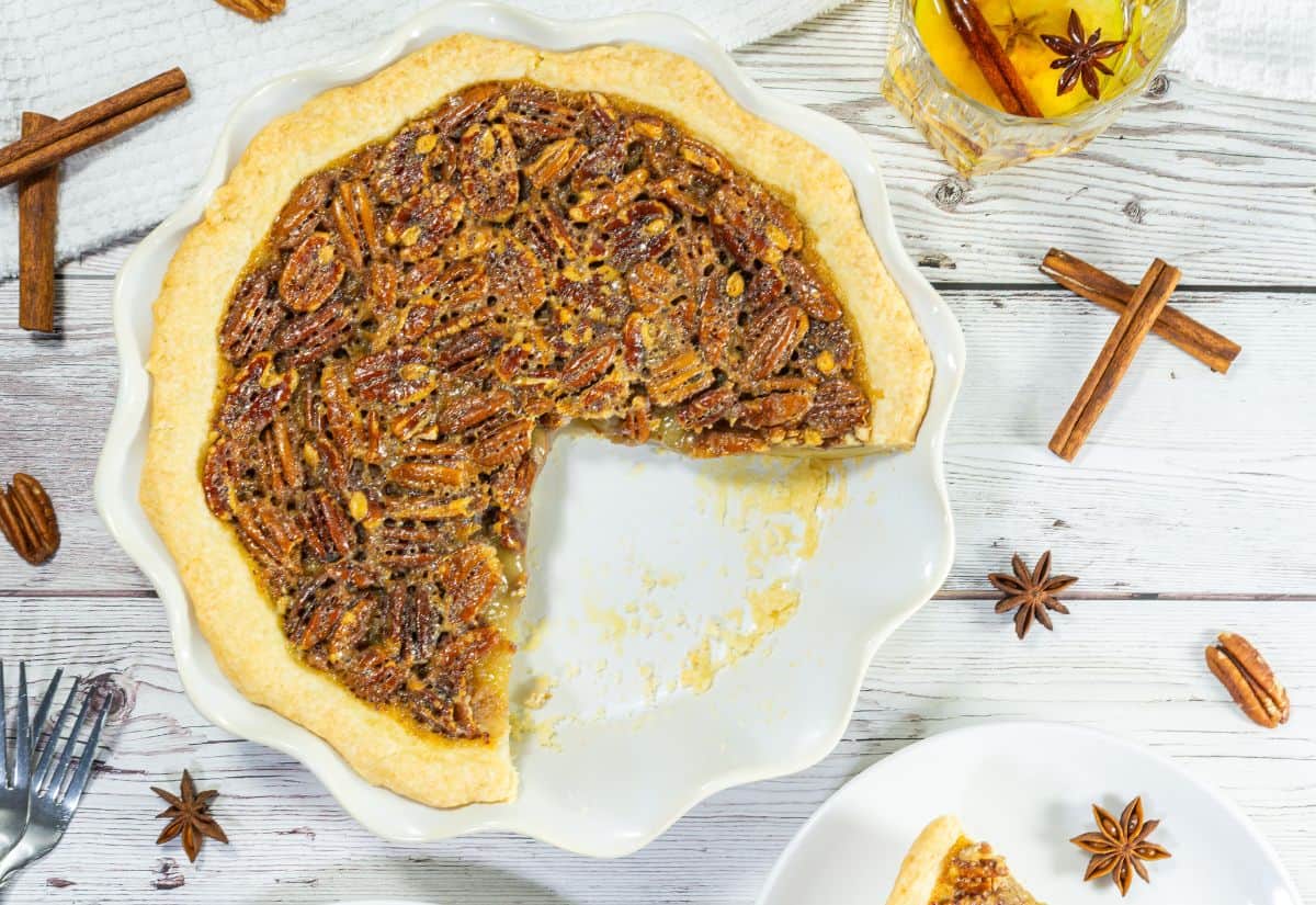 A whole Bourbon Pecan Pie with a slice missing, showing the rich, nutty filling and golden crust.