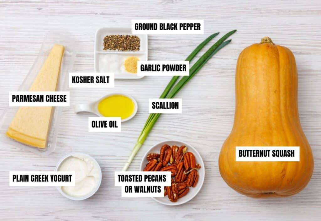 Butternut squash, Parmesan, Greek yogurt, olive oil, pecans, scallions, salt, pepper, and garlic powder arranged on a white surface with labels for each ingredient.